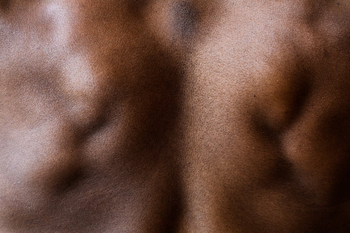 Espalda masculina musculada vista de atrás, con hombros y cintura definidos sobre fondo claro — imagen editorial de banco